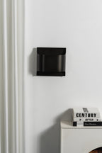 Matte black wall sconce with a rounded globe and warm glow