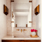 Brass wall sconce shown lit in a warm, styled room