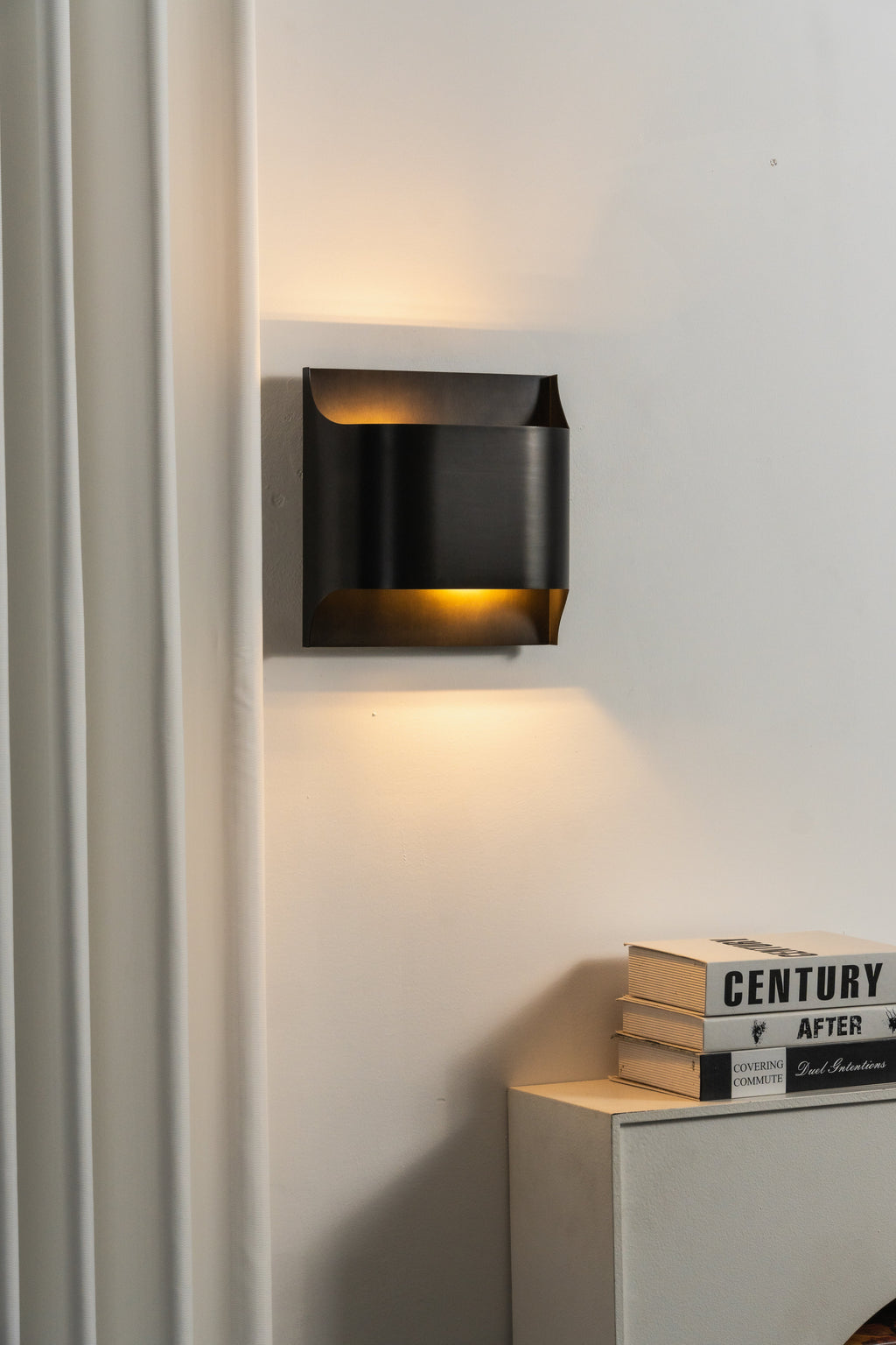Matte black slender wall sconce with a warm filament bulb