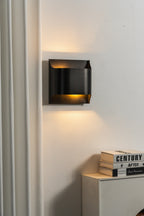 Matte black slender wall sconce with a warm filament bulb
