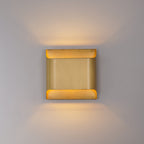 Brass globe wall sconce lit against a soft neutral wall