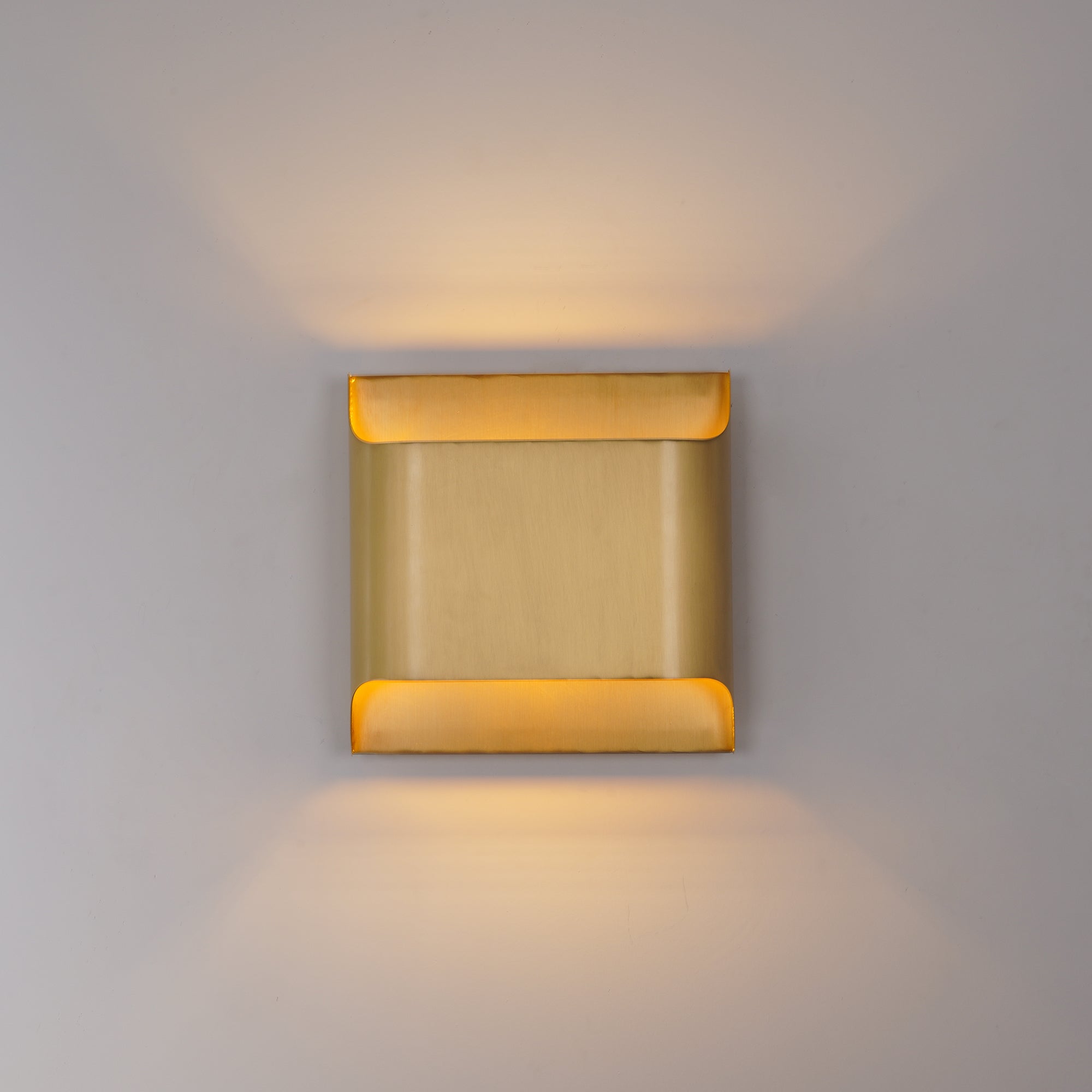 Brass globe wall sconce lit against a soft neutral wall