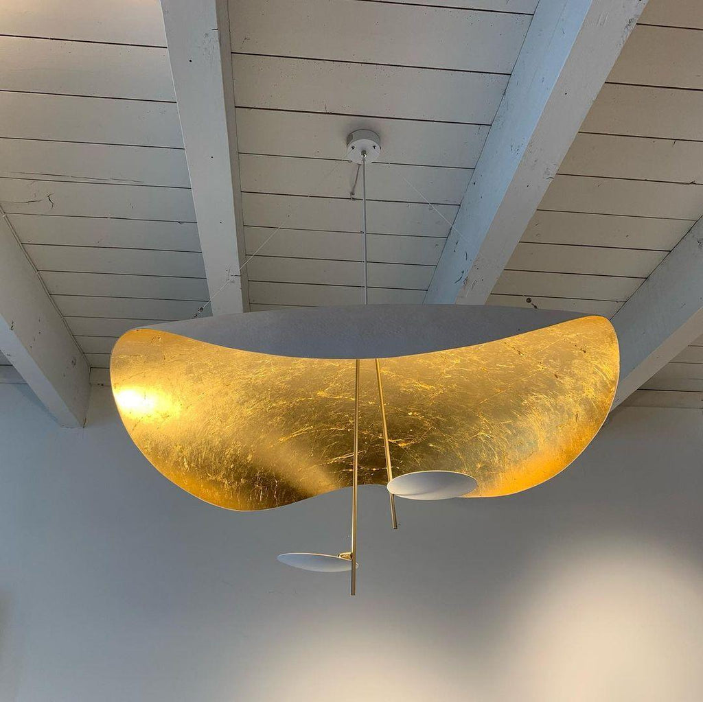 Black and gold curved disc pendant light in a dim room