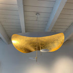 Black and gold curved disc pendant light in a dim room