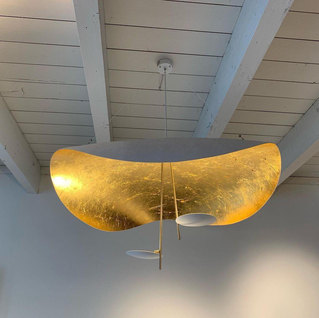 Black and gold curved disc pendant light in a dim room