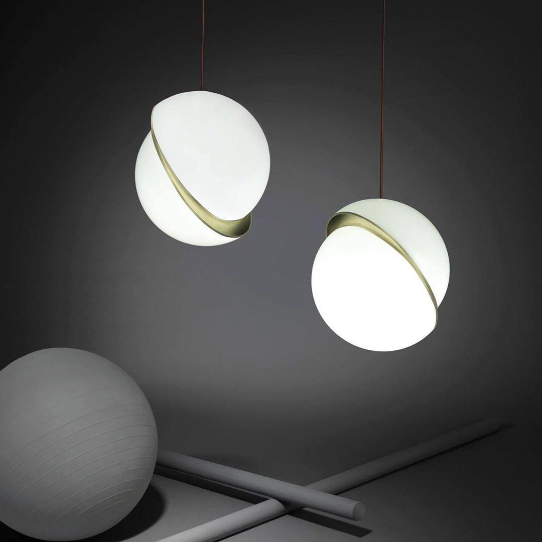 Against a charcoal backdrop, two of this Clérachic pendant hang beside a stone-grey sphere prop and crossed rods.