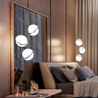 Three of this Clérachic pendant trail from brass rods above a bed, set against a warm wood-panelled headboard wall.