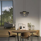 Mouth-blown glass disc pendant light glowing amber in a quiet space