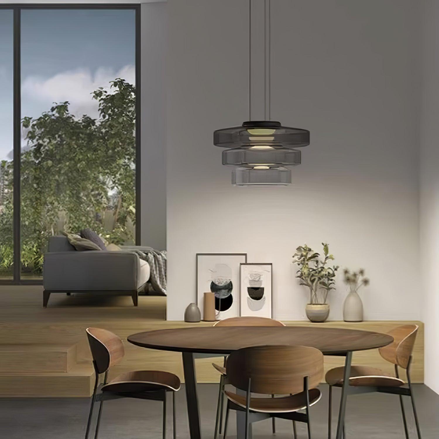 Mouth-blown glass disc pendant light glowing amber in a quiet space