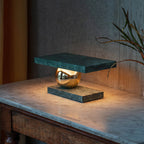 Near a sheer curtain, the Clérachic green marble lamp glows on its marble-topped console table.
