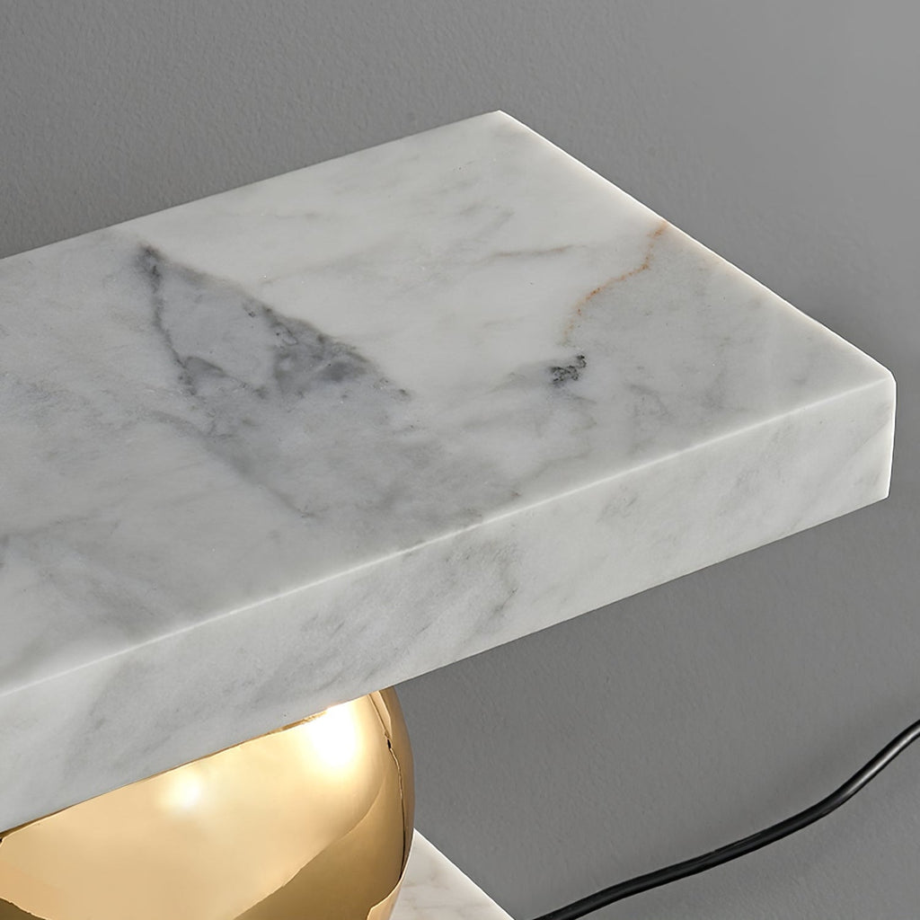 Close-up of the Clérachic white marble slab's veining and its polished brass sphere base, cord visible below.