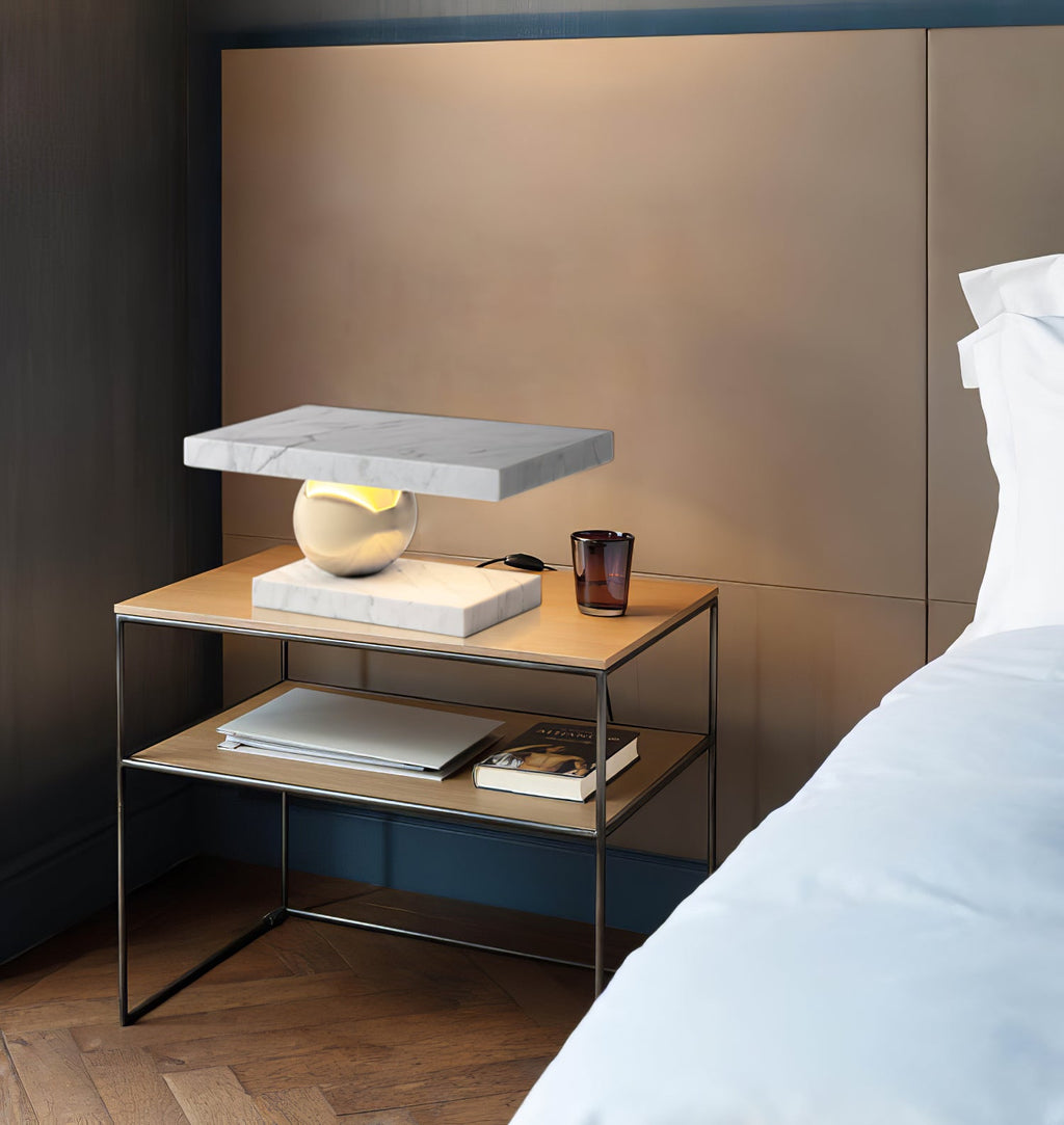 Books and a glass candle jar sit below the Clérachic white marble lamp on its metal-framed bedside table.