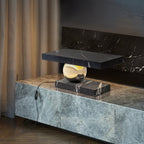 Clérachic black marble table lamp glowing on a stone-clad console beside a curtained fireplace, its cord plugged in.