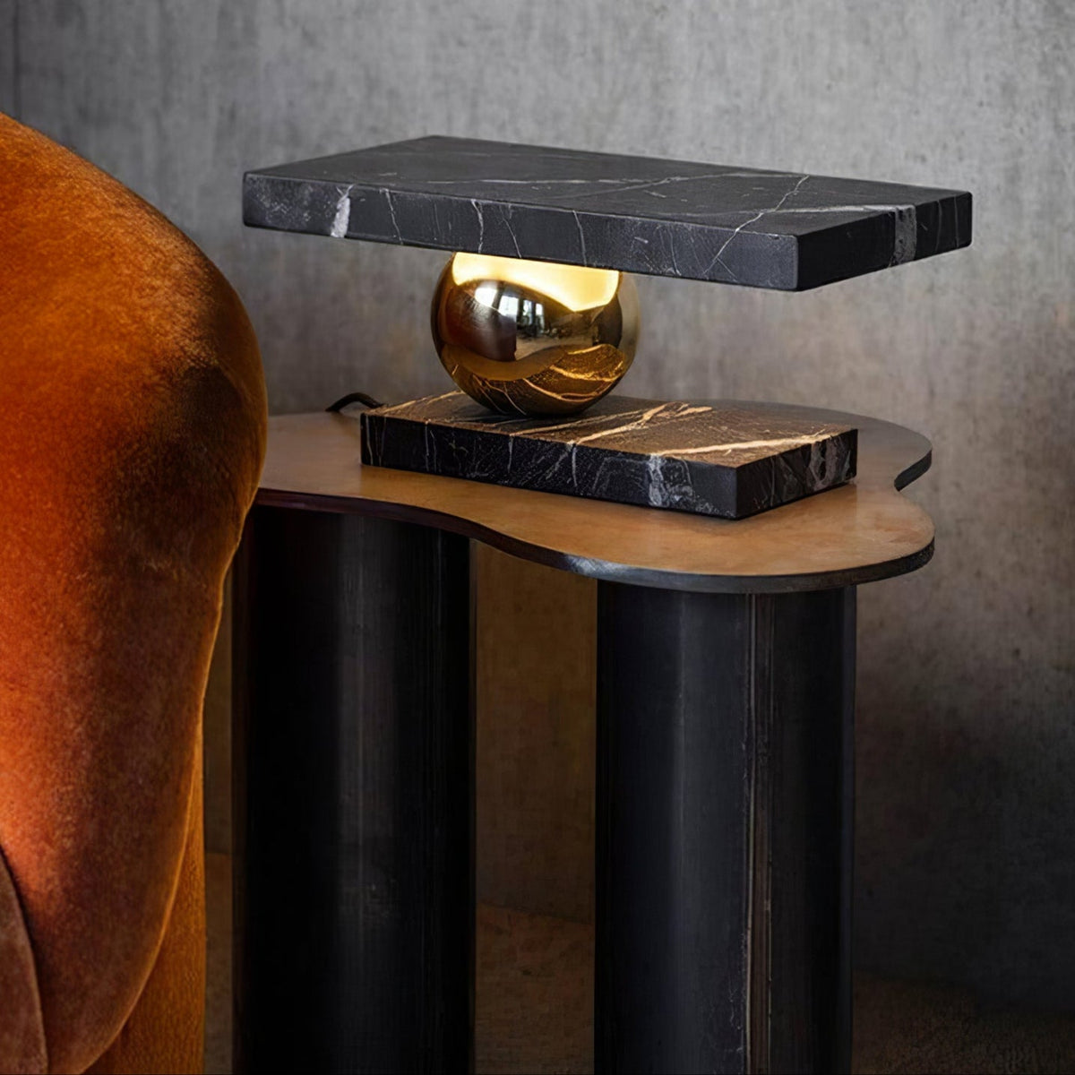 Clérachic black marble table lamp glowing beside the same armchair, framed in a wider view of the room.