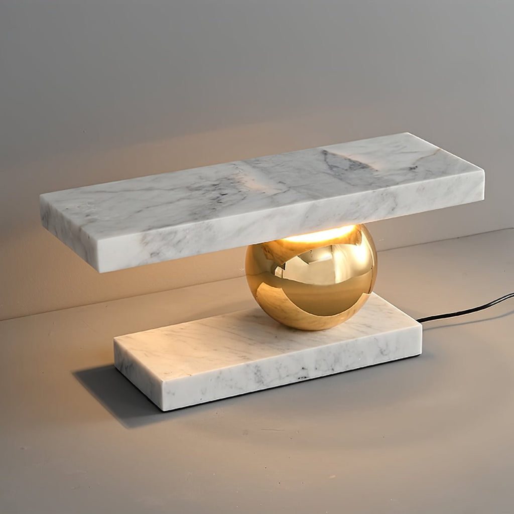 Clérachic white marble table lamp lit against a plain grey background, its power cord visible beside the base.