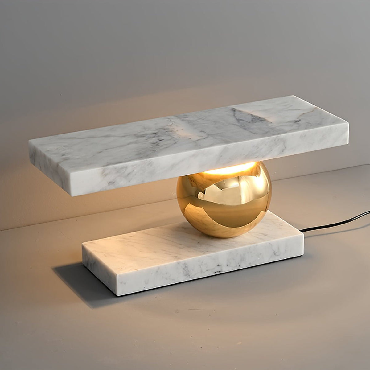 Clérachic white marble table lamp lit against a plain grey background, its power cord visible beside the base.