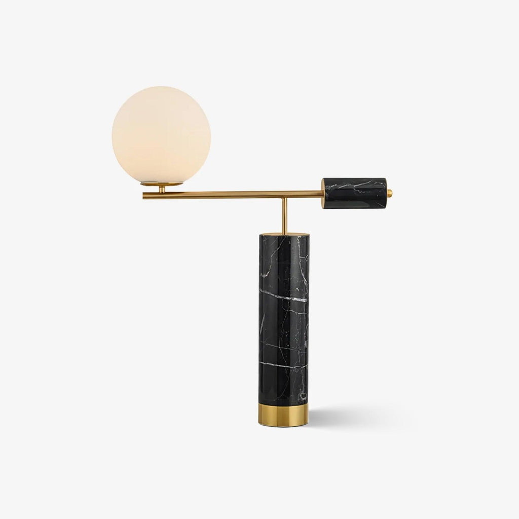 A Clérachic gold table lamp with a black marble base and round white glass globe, shown alone against a plain light backdrop.