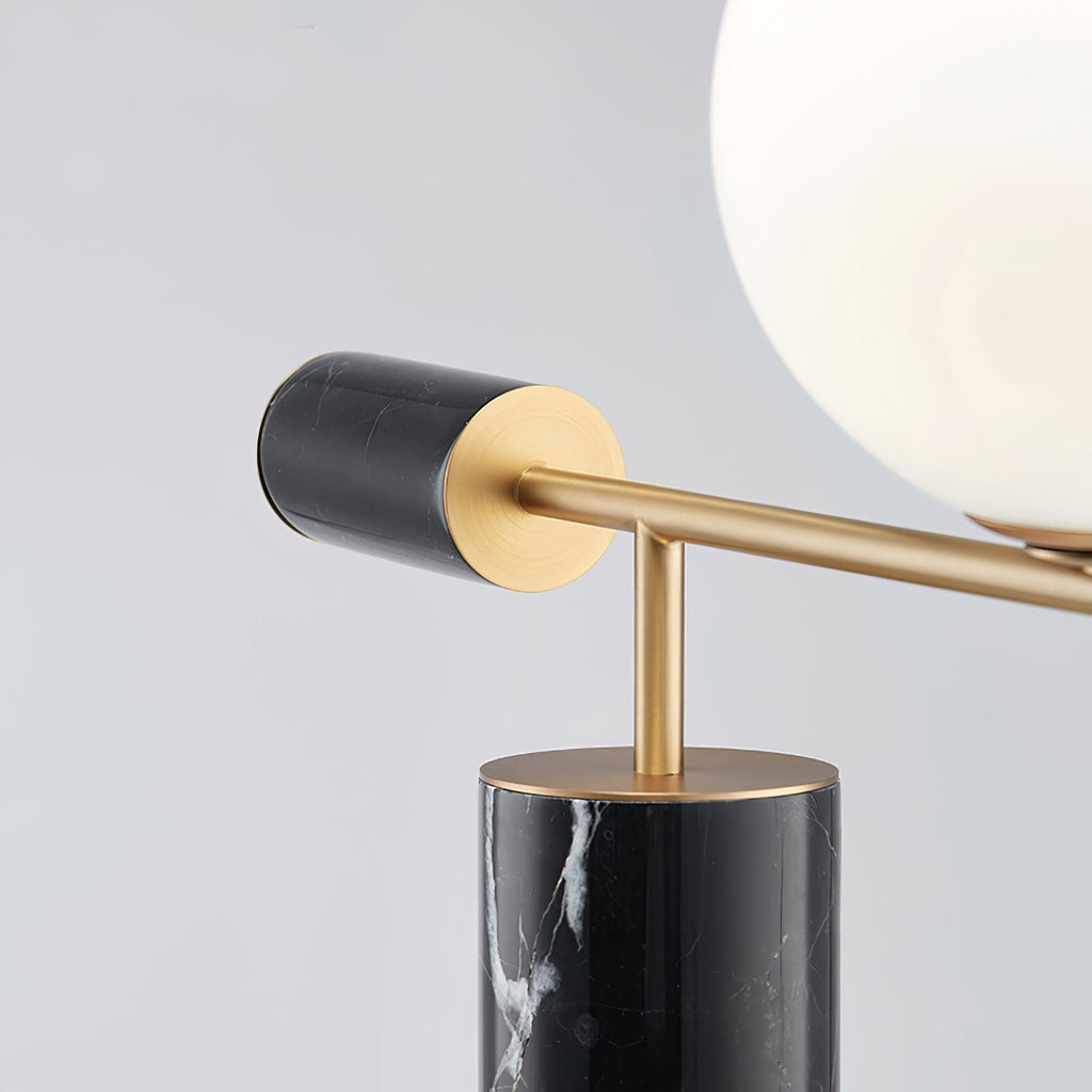 A detail shot of the Clérachic lamp's brass stem meeting its round base plate, the glass globe softly blurred above.