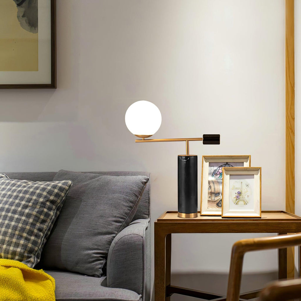 The lit Clérachic lamp sits on a wood side table with framed photographs, a mustard throw draped on the sofa nearby.