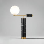 This Clérachic table lamp sits on a grey studio backdrop, its power cord trailing visibly from the black marble base.