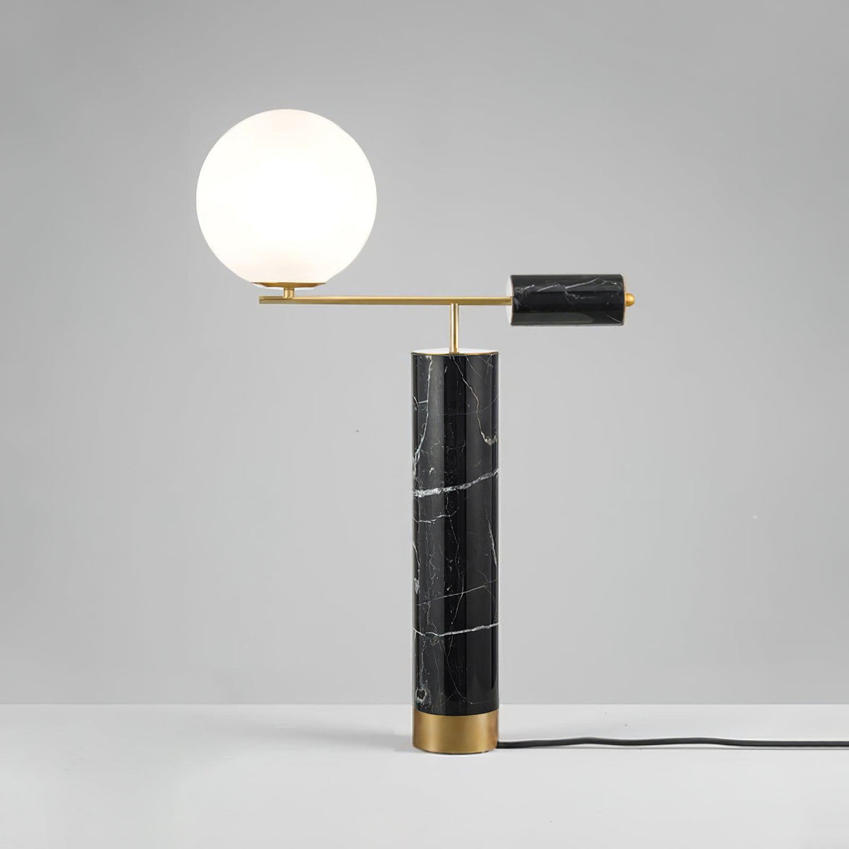 This Clérachic table lamp sits on a grey studio backdrop, its power cord trailing visibly from the black marble base.