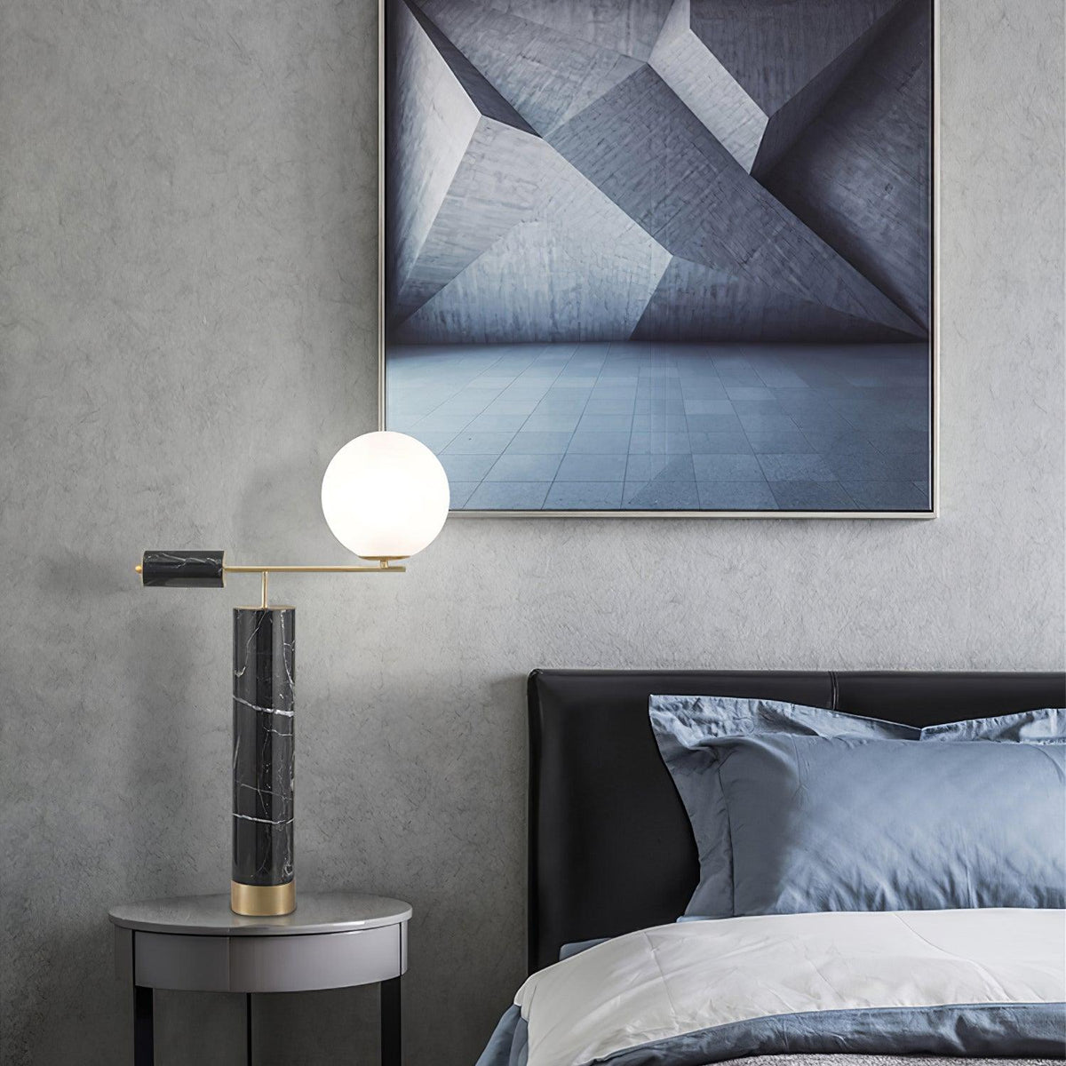 The lit Clérachic lamp glows beside a grey upholstered bed, an abstract framed print hanging on the wall above it.
