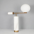 The same white marble Clérachic lamp and stacked books, now framed with the marble finial to the left of the globe.