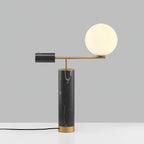 Photographed from a lower, tilted angle, the Clérachic lamp's brass arm carries its glass globe across a grey backdrop.
