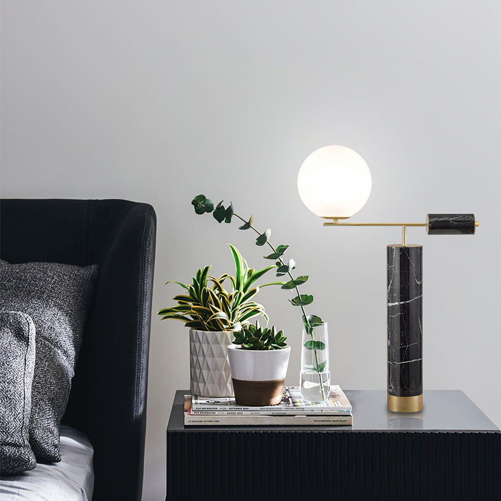 The Clérachic lamp stands on a dark console among potted plants and a stack of magazines, its globe unlit in daylight.