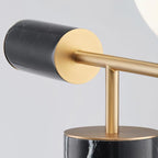 A close-up shows the Clérachic lamp's black marble cap meeting its brass disc and stem above the marble column base.