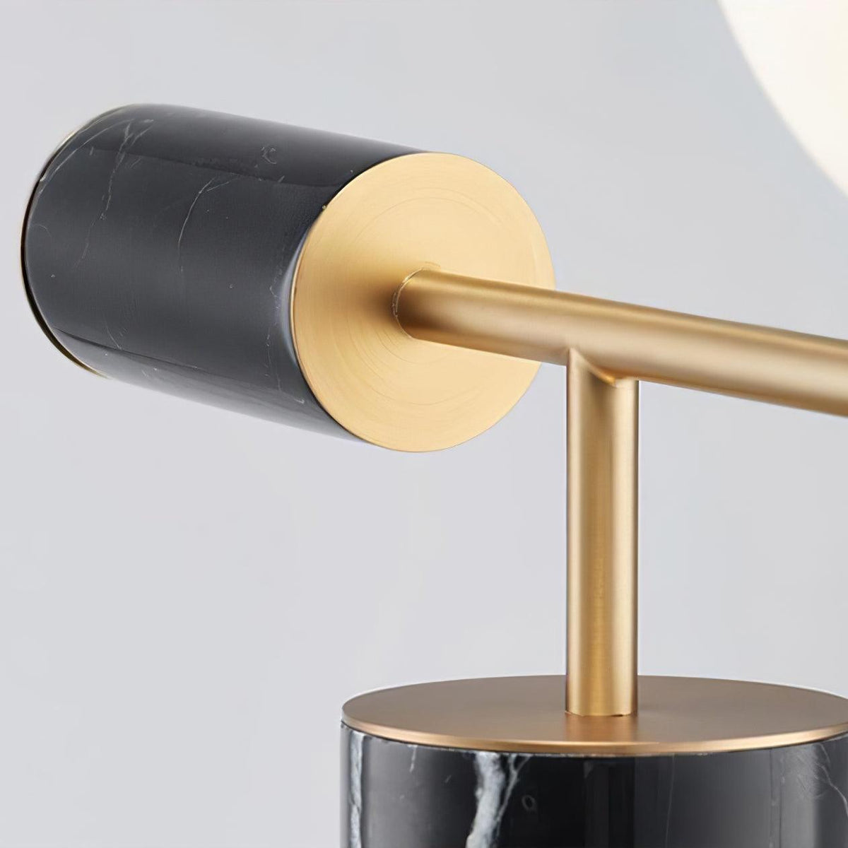 A close-up shows the Clérachic lamp's black marble cap meeting its brass disc and stem above the marble column base.