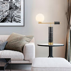 Switched on, the Clérachic table lamp casts a warm glow across the same sofa-side scene, its cityscape print now dimly lit.