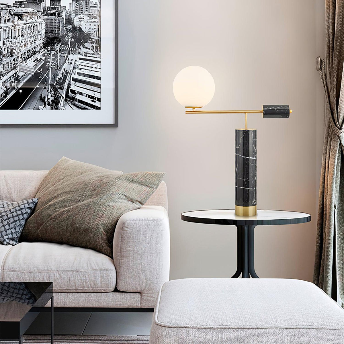 Switched on, the Clérachic table lamp casts a warm glow across the same sofa-side scene, its cityscape print now dimly lit.