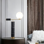 Lit at dusk, the Clérachic lamp glows warmly on the dark console beside houseplants, a faux-fur cushion visible nearby.