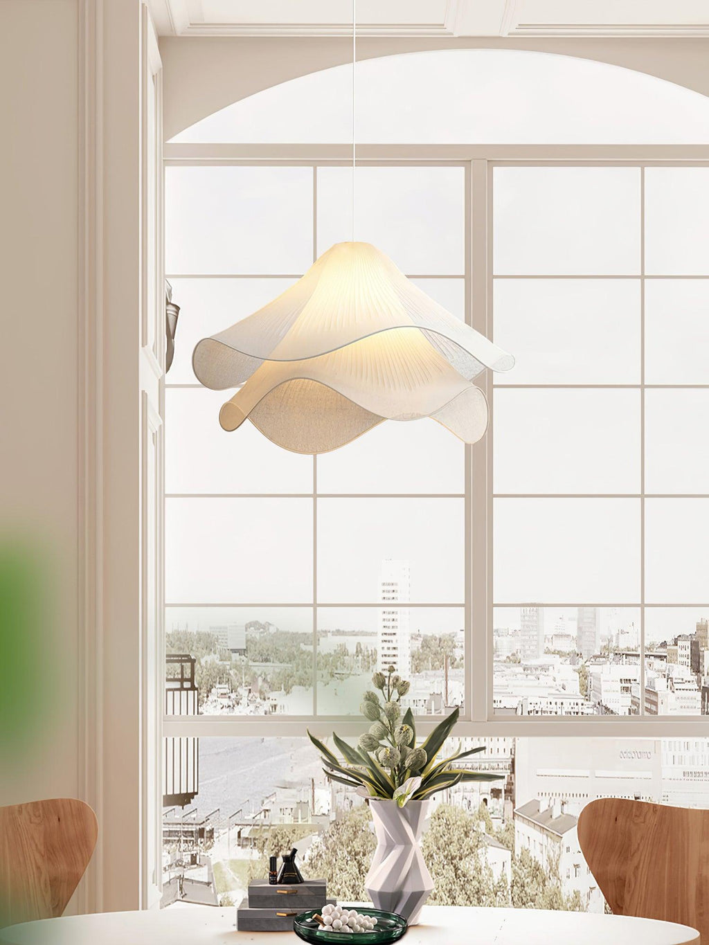 Ethereal Bloom pendant light hanging over a table with warm light through the pleats