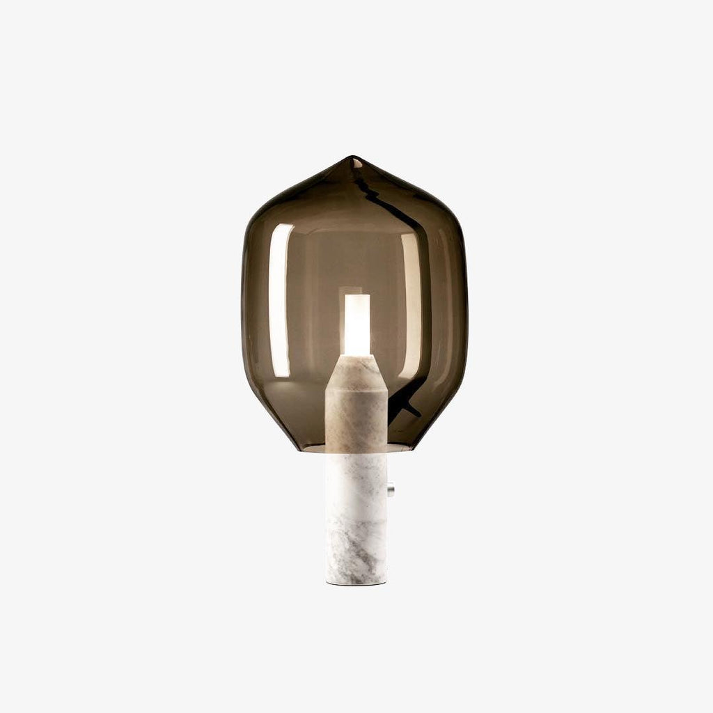 A Clérachic table lamp with an olive-toned glass shade on a white marble base, photographed alone on a plain light backdrop.