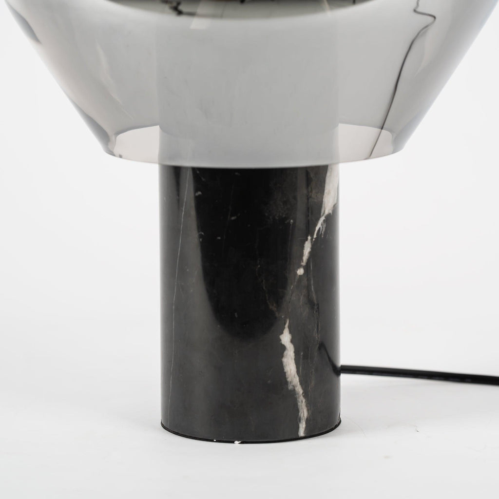 A close crop of the black veined marble base on a Clérachic table lamp, its cord trailing from the socket.
