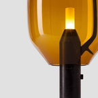 A close crop of Clérachic's amber-glass shade and black base, showing the inline switch button in detail.