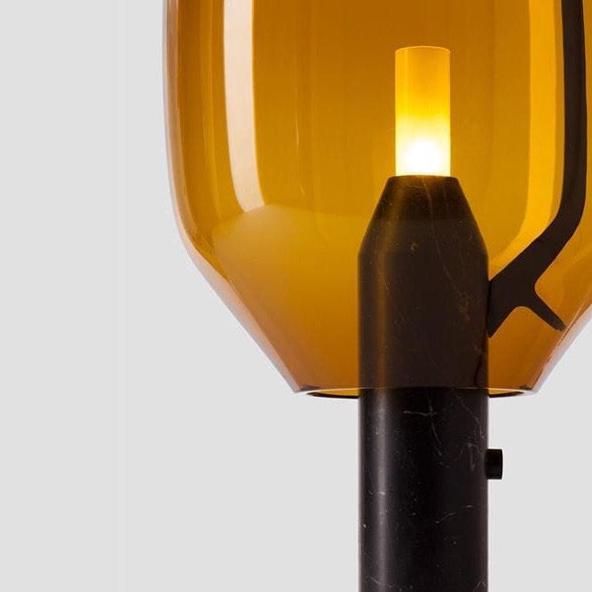 A close crop of Clérachic's amber-glass shade and black base, showing the inline switch button in detail.