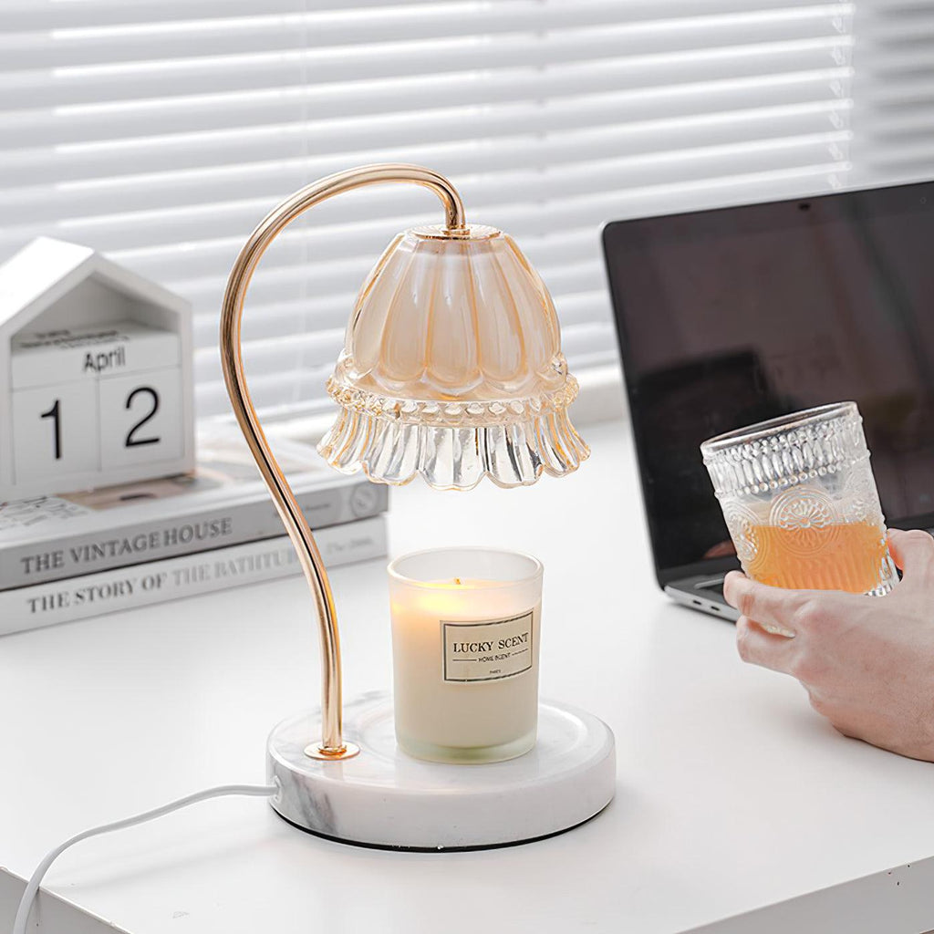 A hand holds a glass of iced drink beside this Clérachic candle warmer lamp, its laptop and desk calendar visible nearby.