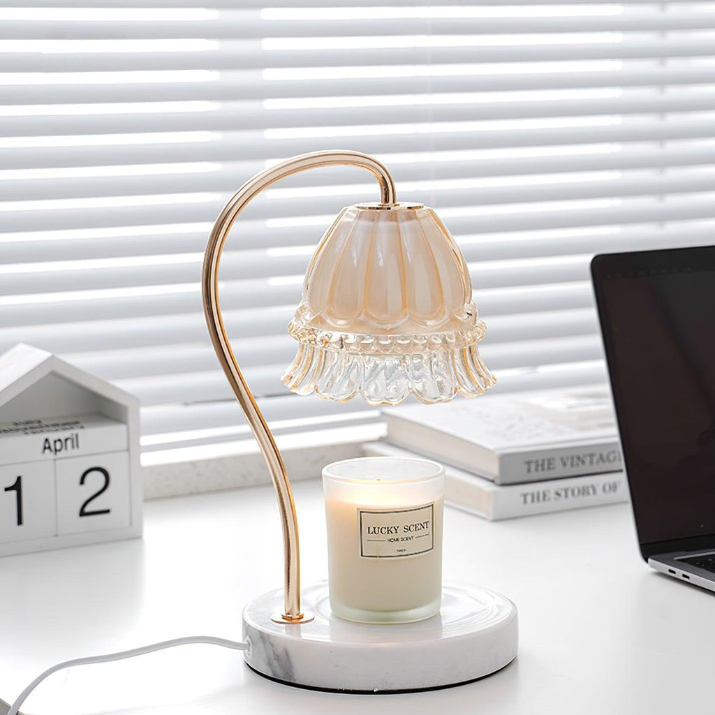 This Clérachic candle warmer lamp stands between a laptop and a stack of books, its candle jar lit beneath the frilled shade.