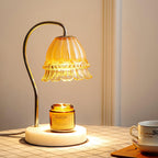 Glowing warmly on a checked tablecloth, this Clérachic candle warmer lamp lights its amber candle jar beside a teacup.