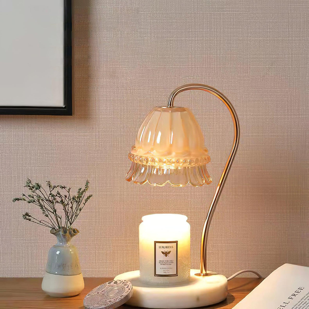On a wood surface against linen wallpaper, this Clérachic candle warmer lamp stands near a small vase of dried flowers.