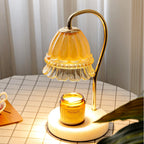On a checked tablecloth beside a teacup, this Clérachic candle warmer lamp's glow lights an amber candle jar beneath its shade.