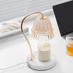 A glass of iced drink sits beside this Clérachic candle warmer lamp, photographed on a desk in front of venetian blinds.