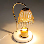 In a dimly lit room, this Clérachic candle warmer lamp's frilled glass shade glows warmly above its lit candle jar.