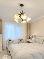 Above a cream bed and vanity mirror, this Clérachic chandelier lights a soft bedroom.