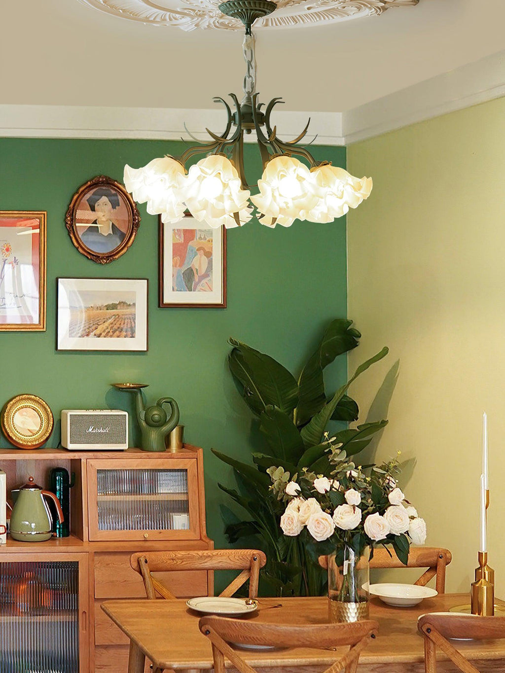 In a green-walled dining nook with a gallery wall, this Clérachic chandelier glows above a small wooden table.