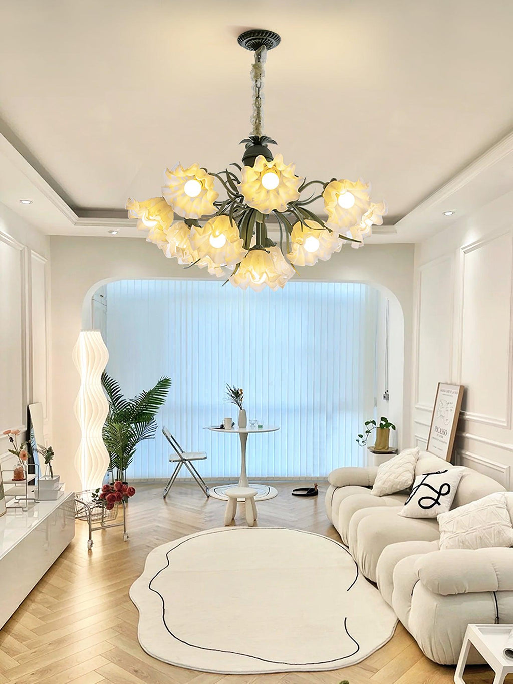 Through an arched doorway in a living room with a round rug, this Clérachic chandelier lights the space.