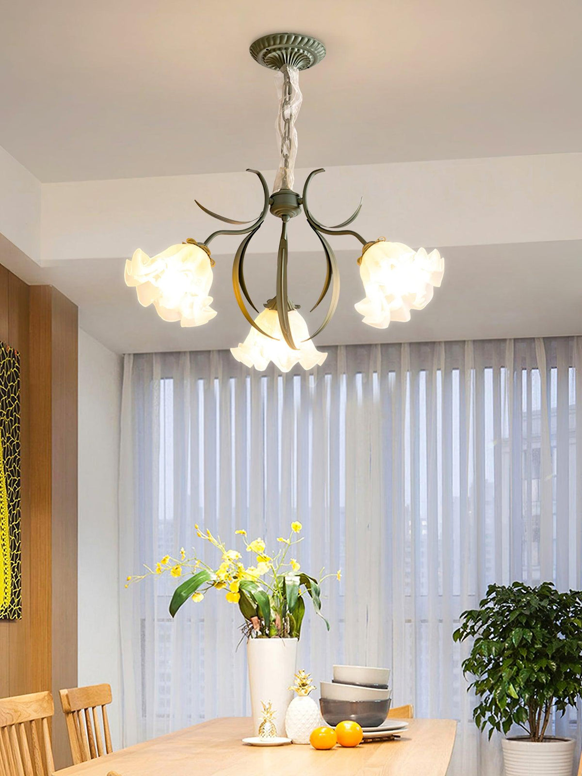 In a bright room with sheer curtains, a dark-bronze version of this Clérachic chandelier hangs unlit above a dining table.